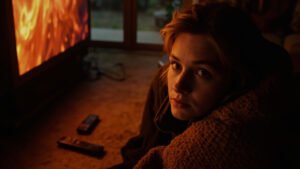 A viewer engrossed in a television screen with face illuminated by the glow, surrounded by remotes and a cozy blanket