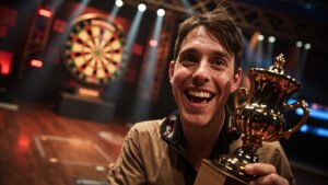 Luke Littler celebrating his World Grand Prix victory holding the trophy on stage with triumphant expression